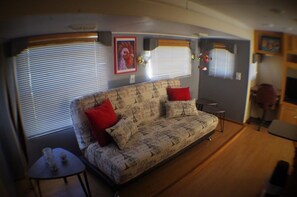 Un intérieur de camping-car chaleureux, avec un canapé à motifs, des coussins rouges et une petite table.