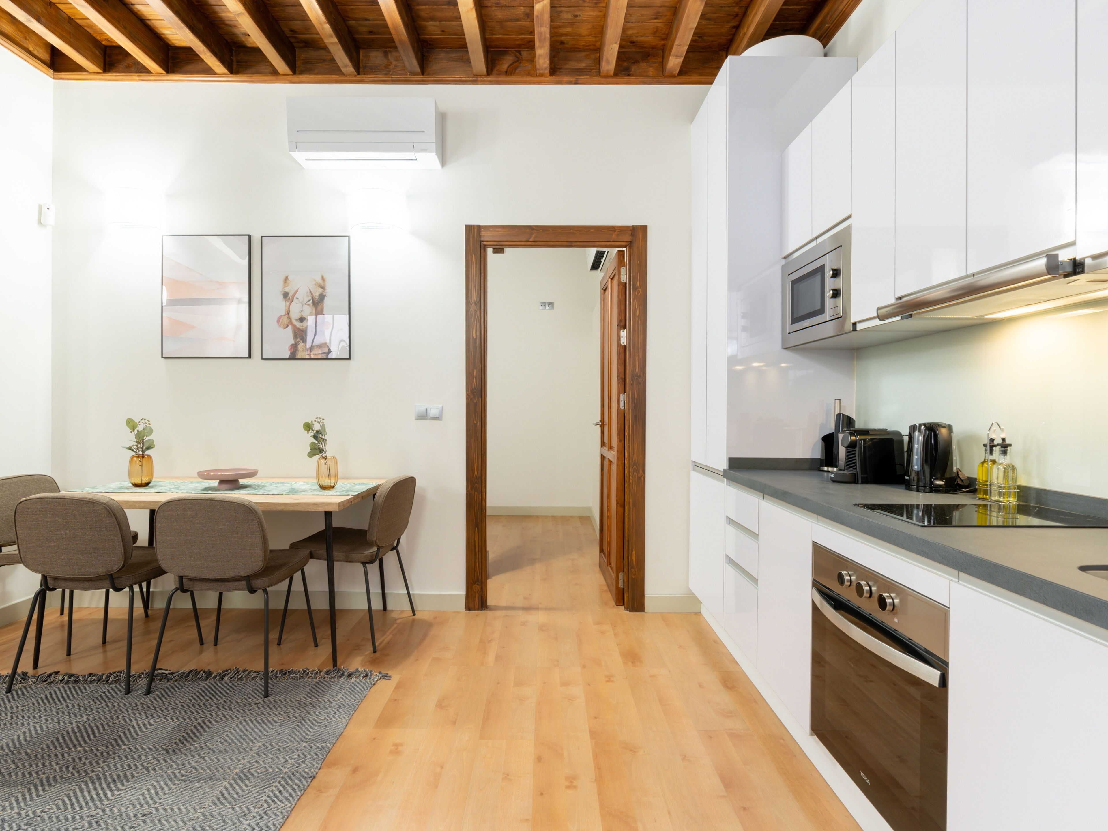 A modern kitchen with white cabinets, a built-in oven, and a microwave.