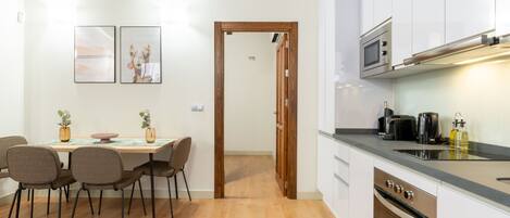 A modern kitchen with white cabinets, a built-in oven, and a microwave.