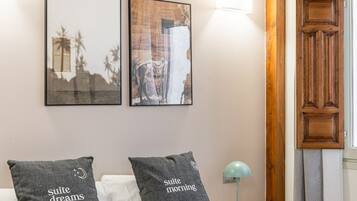 A bedroom with a bed, two pillows, a nightstand, a lamp, and two framed pictures on the wall.