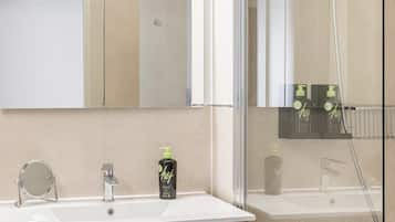 A modern bathroom with a large mirror, a sink, a wooden vanity, and a glass-enclosed shower area.