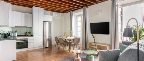 Eine moderne Küche mit weißen Schränken, einem Edelstahlkühlschrank und einem Essbereich mit rundem Tisch und Stühlen.