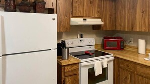 Una cucina con mobili in legno, un frigorifero bianco, un fornello e un forno a microonde.