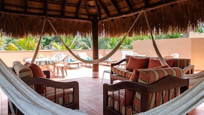 A covered outdoor seating area with hammocks and cushioned chairs, a thatched roof, and a view of lush greenery. - Low Season rate!
 Cozy 3 house, close to the beach, w/private pool and BBQ (Playa del Carmen)