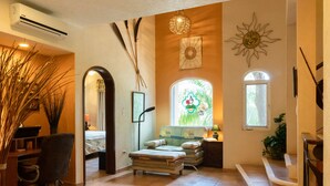 A hotel room with a bed, a desk, a chair, a window with a view, and a sun decoration on the wall. - Low Season rate!
 Cozy 3 house, close to the beach, w/private pool and BBQ (Playa del Carmen)