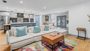 A modern living room with a sectional sofa, a wooden coffee table, and a colorful rug. - Luxury Oasis w/ Private Pool - 5-Minutes to Beach (Seminole)