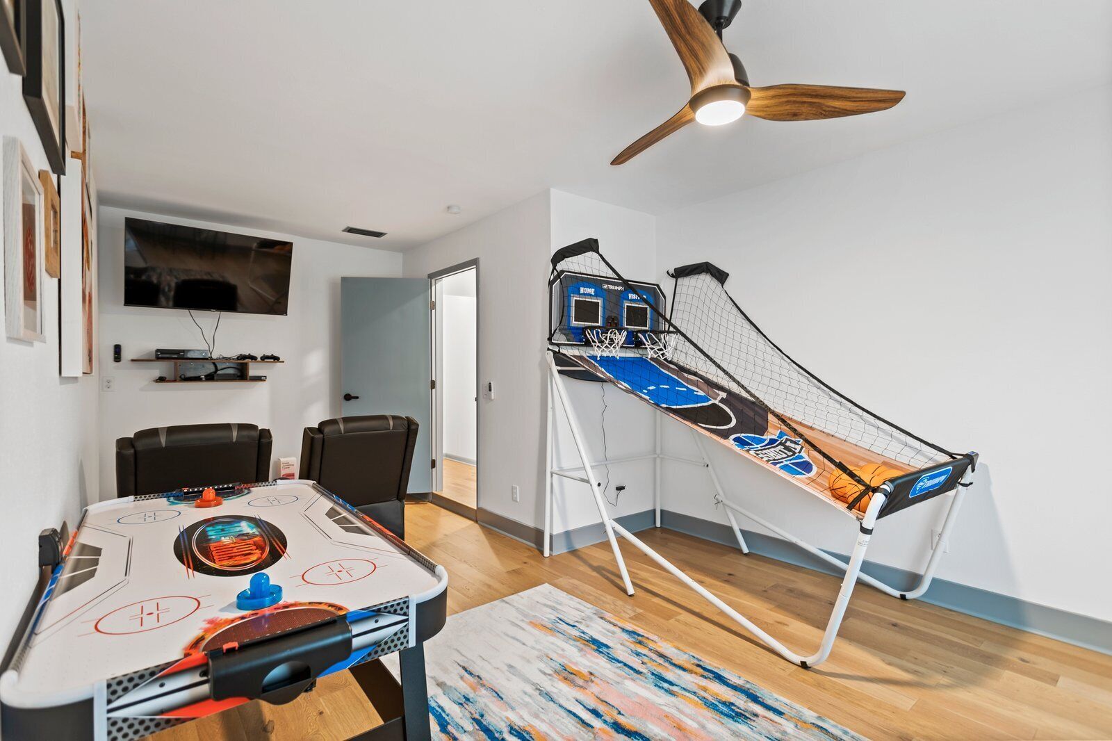 Ein Zimmer mit Tischtennisplatte, Deckenventilator und an der Wand befestigtem Fernseher.