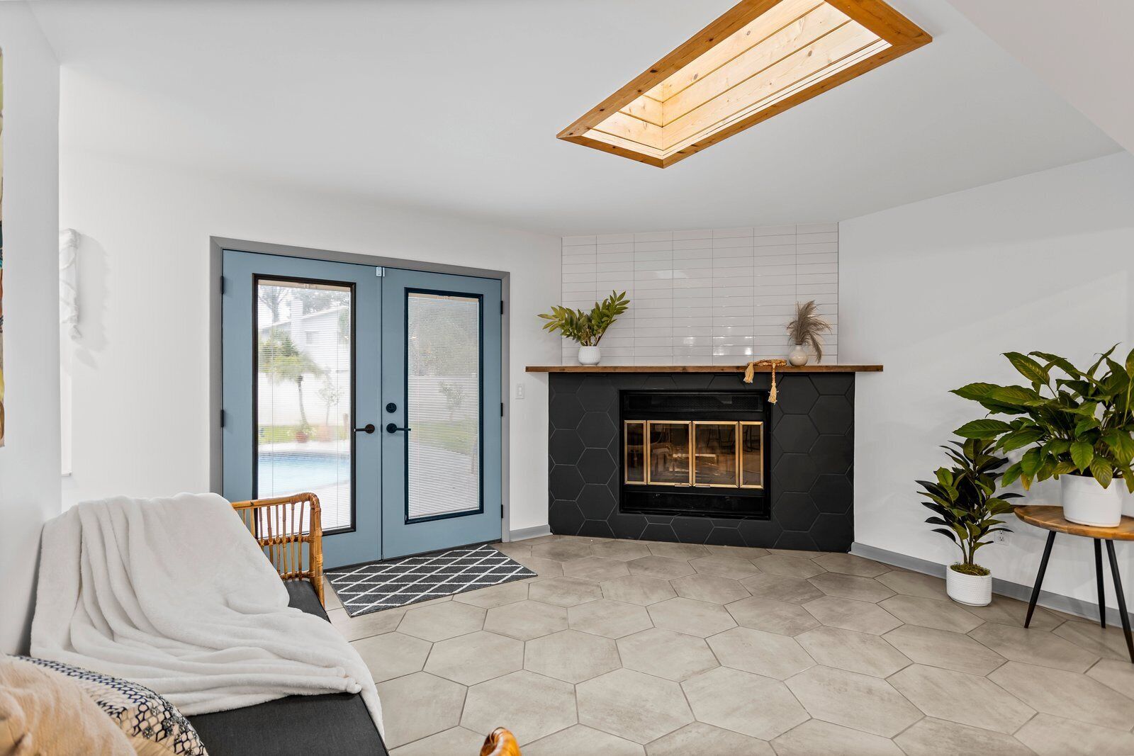 Una sala de estar moderna con chimenea, una puerta azul y vistas al exterior.