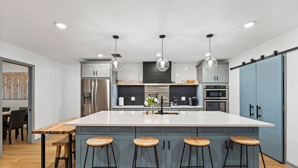 A modern kitchen with a large island, bar stools, stainless steel appliances, and pendant lighting. - Luxury Oasis w/ Private Pool - 5-Minutes to Beach (Seminole)