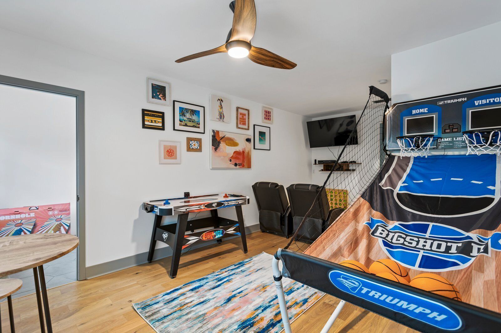 A room with a foosball table, a basketball hoop, and a TV mounted on the wall.