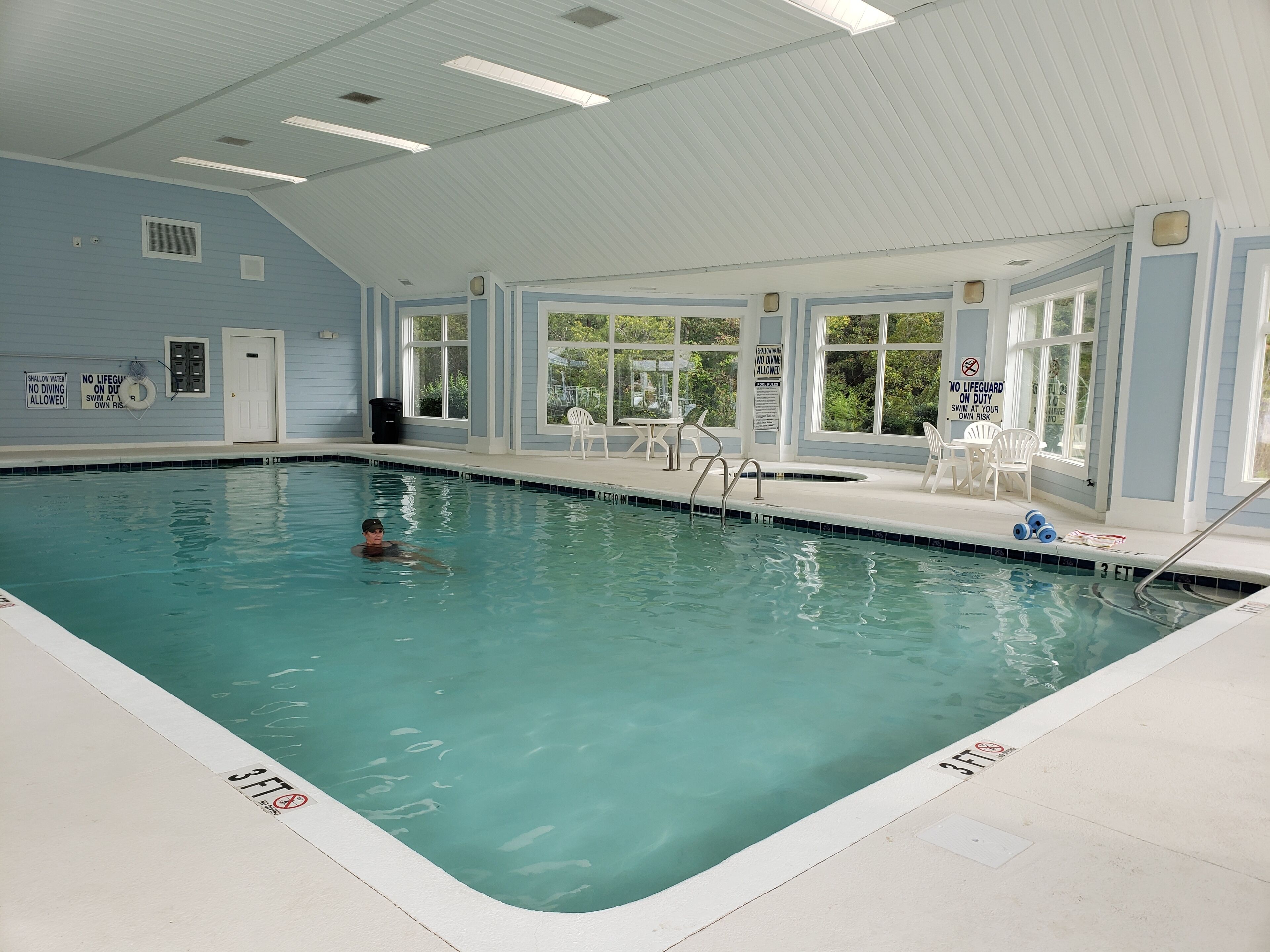 Une piscine intérieure à l’eau claire, avec des repères indiquant la profondeur et des panneaux de sécurité.