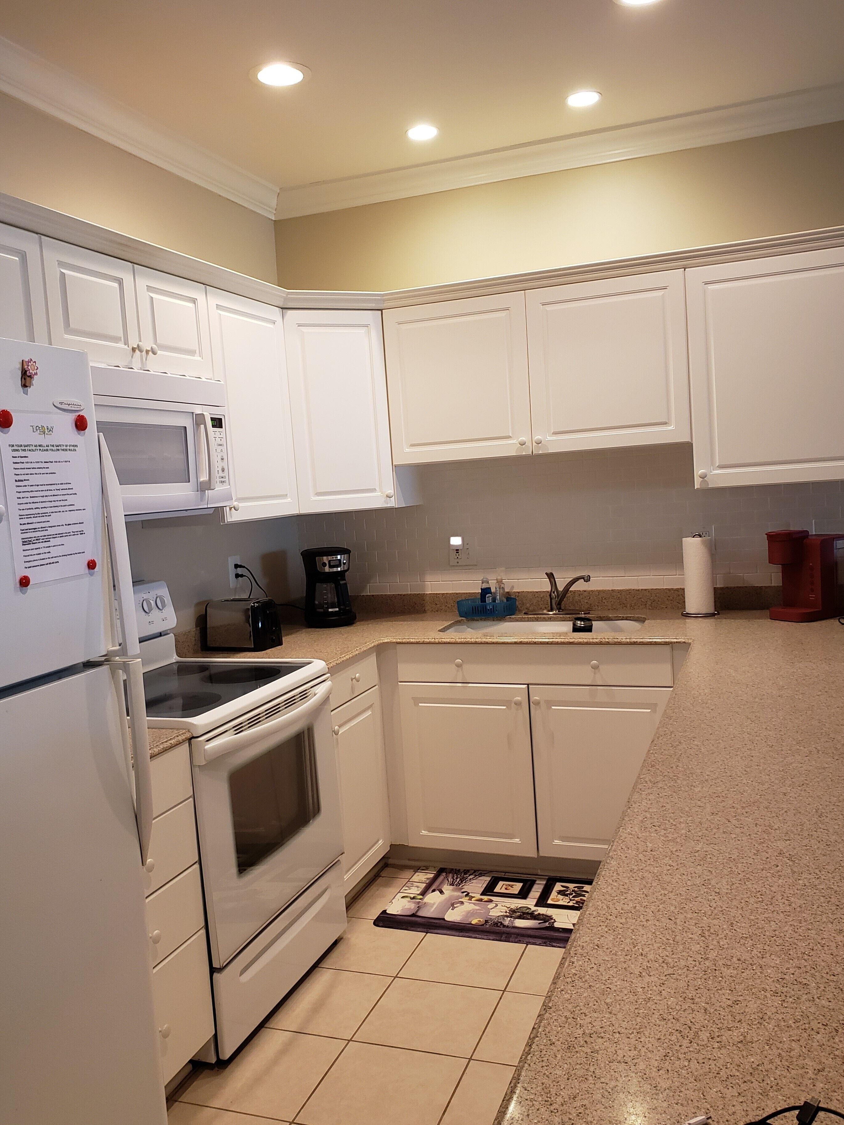 A kitchen with white cabinets, a microwave, a stove, and a refrigerator.