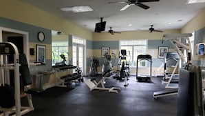 Een sportschool met plafondventilatoren, trainingsapparatuur en grote ramen.