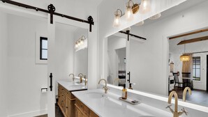 Ein modernes Badezimmer mit zwei Waschbecken, Holzschränken und einem großen Spiegel.