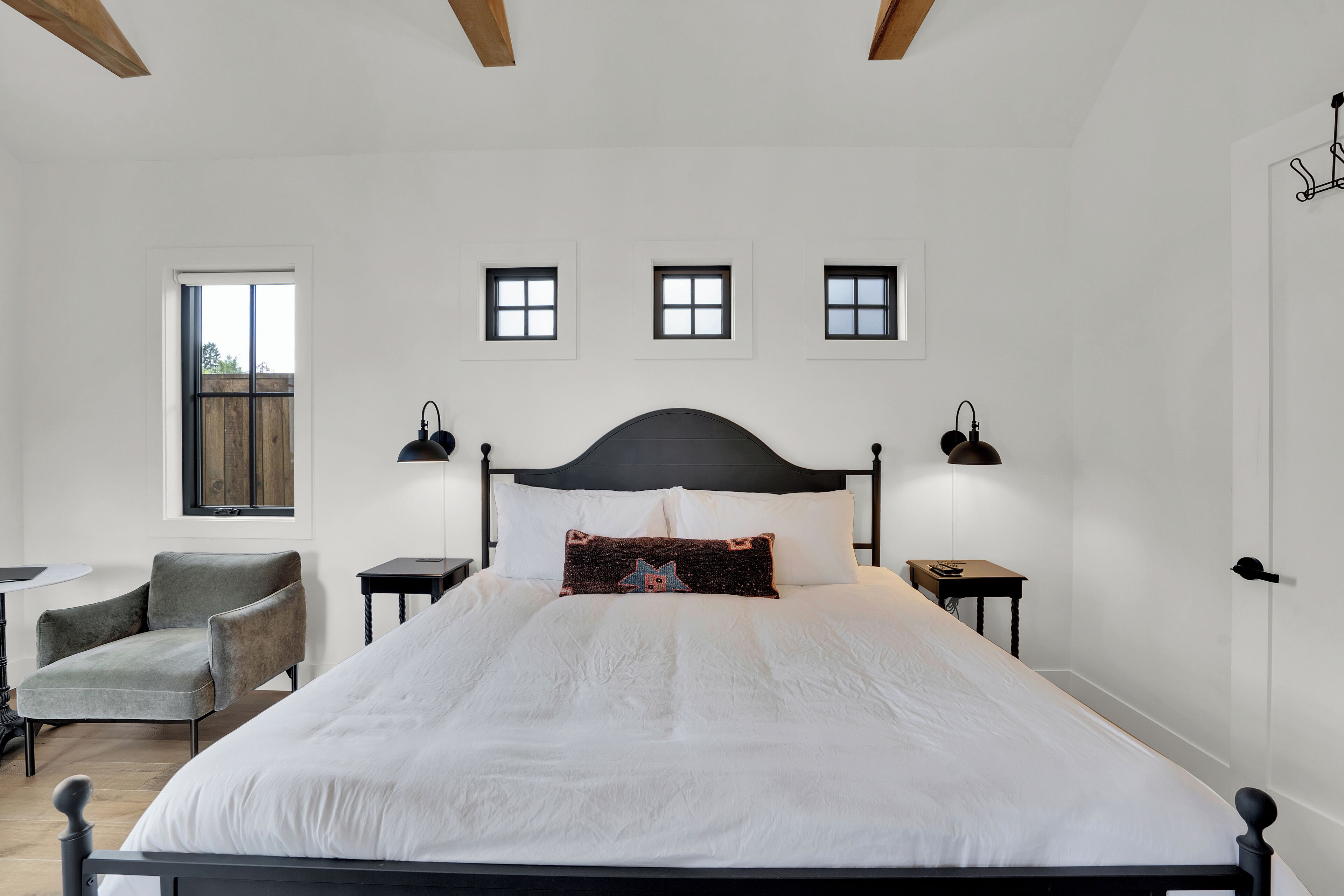 A bedroom with a large bed, two bedside tables, a chair, and a window.