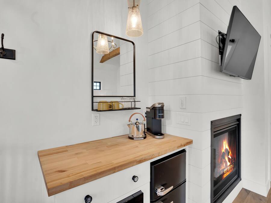 Una cocina moderna con encimera de madera, cafetera, hervidor y chimenea.