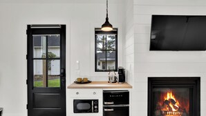 Eine moderne Küche mit einem schwarzen Kühlschrank, einem eingebauten Backofen und einem schwarzen Geschirrspüler. Über der Spüle befindet sich ein Fenster und eine flachbildschirmige Fernsehgerät ist an der Wand montiert.