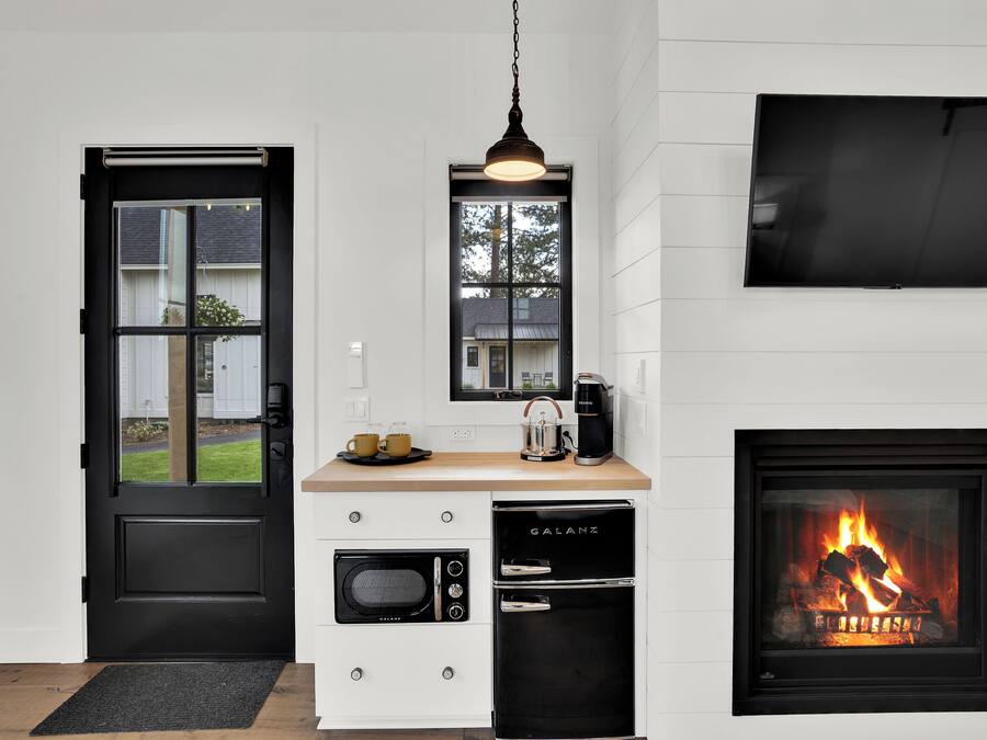 Een moderne keuken met een zwarte koelkast, een inbouwoven en een zwarte vaatwasser. Er is een raam boven de gootsteen en een flatscreen televisie aan de muur bevestigd.
