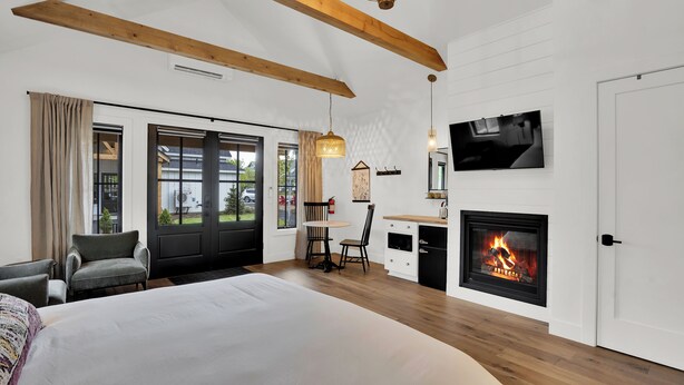Ein modernes Hotelzimmer mit einem großen Bett, einem Schreibtisch mit Kamin und einem an der Wand befestigten Fernseher.