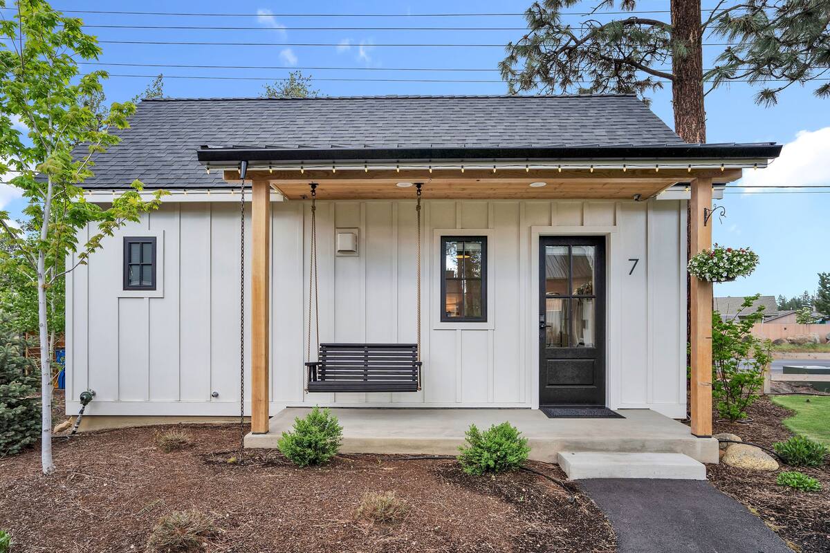 A small, single-story house with a porch, a black door, and a number '7' on the front.