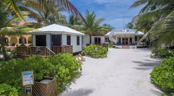 A resort with white buildings, a sandy pathway, and lush greenery.