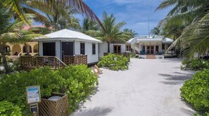 Ein Resort mit weißen Gebäuden, einem Sandweg und üppigem Grün.