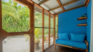 A room with a wooden floor, a blue sofa, and a large window overlooking greenery.