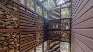 A corner room with a stone wall, wooden slats, and a small window.