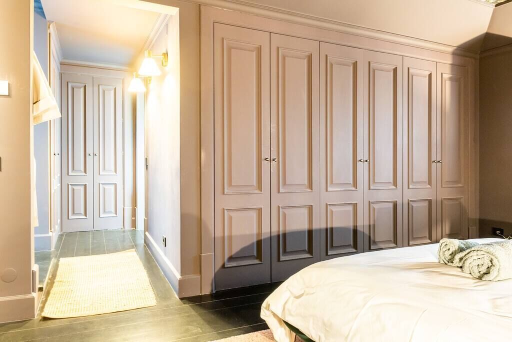 Une chambre à coucher avec un grand lit, une armoire et une salle de bain visible au fond.