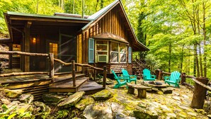 Una cabaña de madera con porche, escalones de piedra y mobiliario exterior.