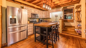 Una cocina con vigas de madera, electrodomésticos de acero inoxidable y una isla central con taburetes de bar.