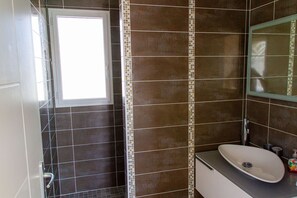 Une salle de bain avec un lavabo blanc, un miroir et une fenêtre.