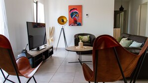 Ein modernes Wohnzimmer mit Fernseher, einem runden Couchtisch und zwei Ledersesseln.