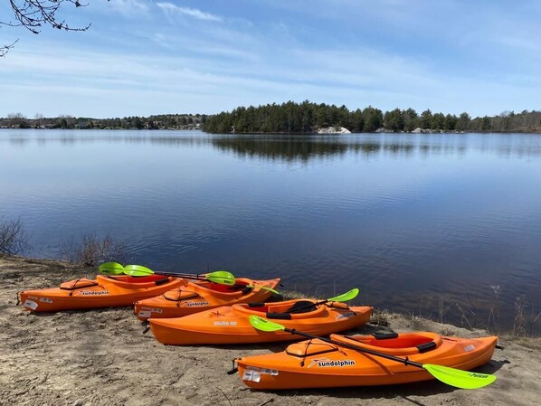 A calm lake with kayaks lined up on the shore.