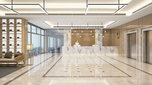 Un moderno vestíbulo de hotel con mostrador de recepción, zona de estar y grandes ventanales con vistas a la ciudad.