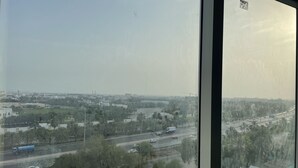 Vista desde un piso alto con vistas a un paisaje urbano que incluye una autopista, edificios y áreas verdes.