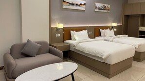 Habitación de hotel con dos camas, un sofá, una mesita y obras de arte en la pared.