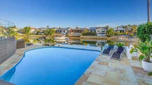 A swimming pool with lounge chairs, a view of houses, and a clear sky.