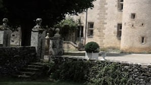 Un bâtiment en pierre doté d’une tour, de statues et d’un jardin bien entretenu.