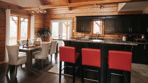 A wooden cabin interior with a kitchen, dining area, and bar seating.