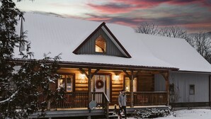 A log cabin with a porch, a triangular roof, and a visible chimney.