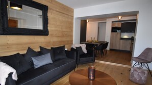 A modern living room with a black sofa, a round coffee table, and a wooden floor. - L'Étendard appartement 5 (Vaujany)