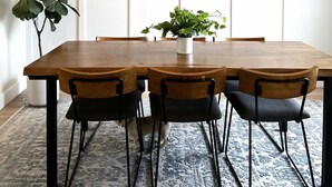 A dining area with a wooden table, black chairs, a hanging geometric chandelier, and a potted plant. - Updated Great Location Beautiful New House (Thornton)