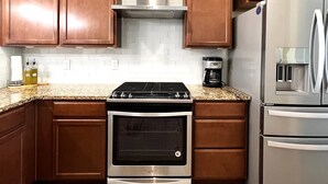 A kitchen with wooden cabinets, a stainless steel stove, a coffee maker, and a refrigerator. - Updated Great Location Beautiful New House (Thornton)