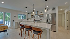 A modern kitchen with a large island, stainless steel appliances, and pendant lighting. - Lakefront Hideaway on Hartwell (Lavonia)