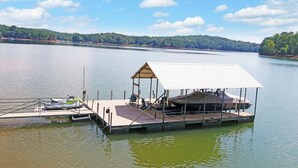 A dock with a covered boat storage area, a small seating area, and a boat moored at the dock. - Lakefront Hideaway on Hartwell (Lavonia)