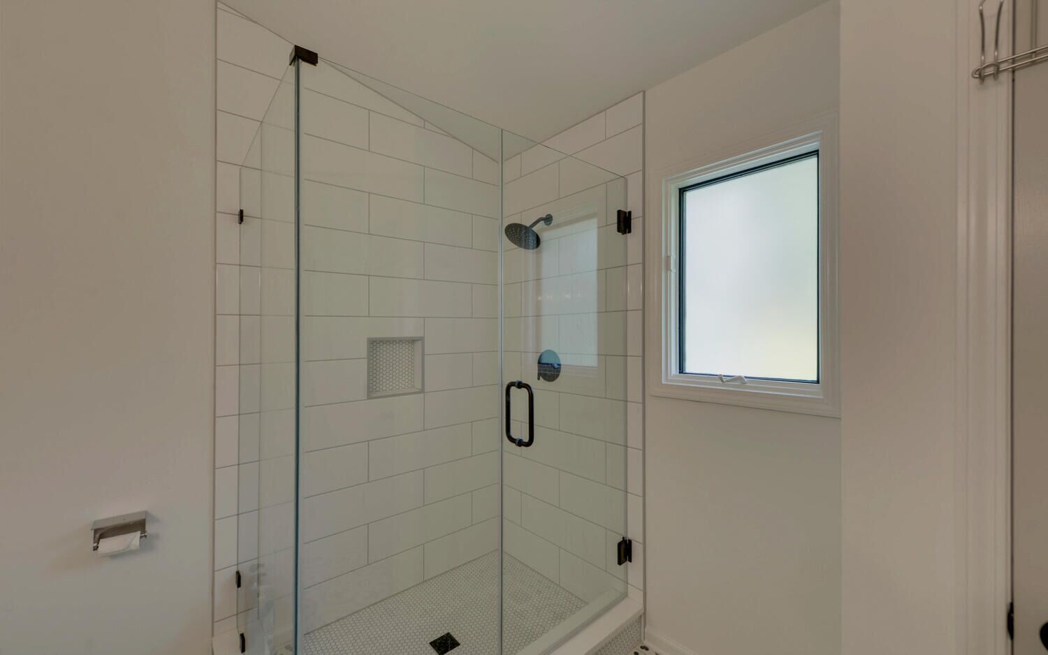 Une salle de bain moderne avec une douche à parois de verre, une petite fenêtre et un sol carrelé.