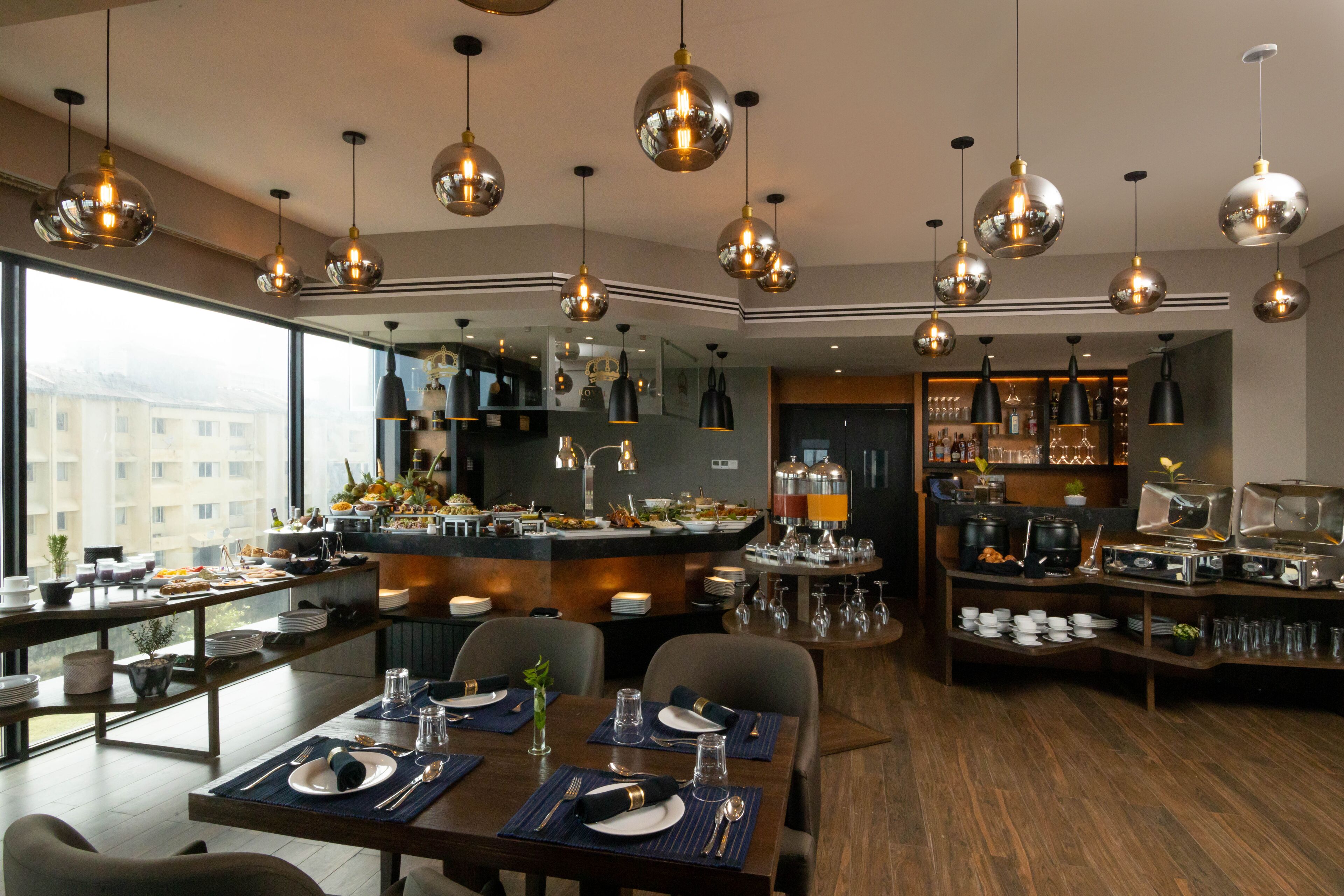 A modern dining area with multiple tables, a central bar, and a view of the city.