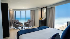 A hotel room with a large bed, two armchairs, a small table with a plant, and a view of the ocean. - MaRadha Colombo (Colombo)
