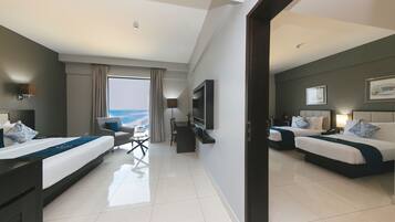 Habitación de hotel con dos camas, un escritorio y vista al océano.